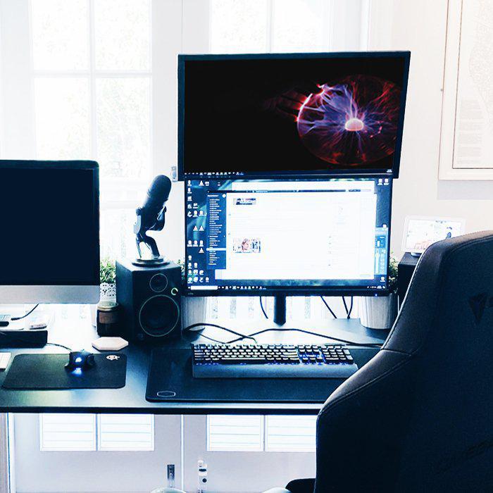 Desk setup with multiple monitor screens and microphone stand